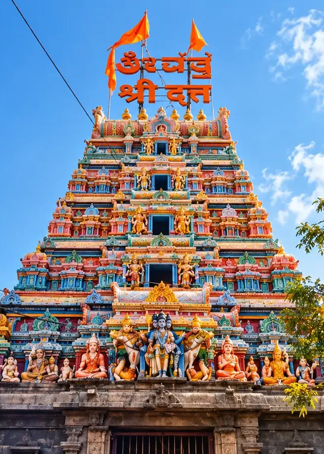 Temple tower at Gangapur with an orange Dattatreya banner against a blue sky